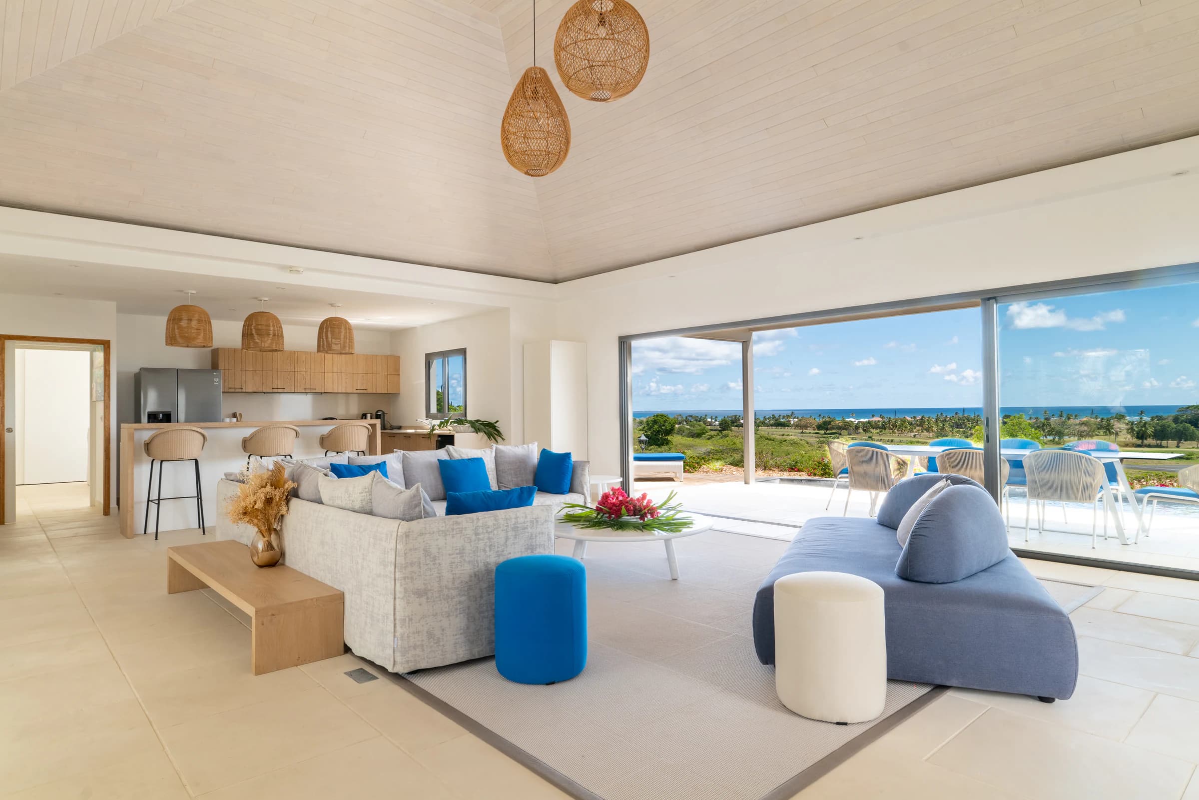 Plateau Dominant — pièce à vivre ouverte avec cuisine, salon et baie vitrée donnant sur terrasse, piscine à débordement et vue mer, villa livrée 2021-2023, Saint-François